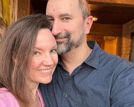Man and woman posing closely together indoors with wooden beams in the background